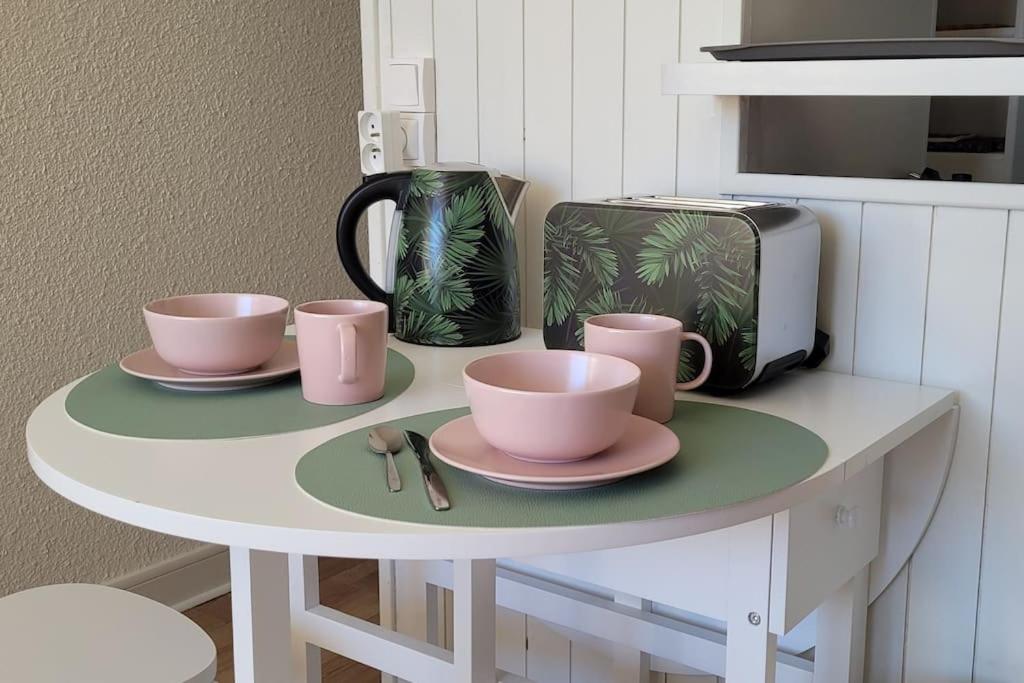 a table with two pink cups and a toaster at Appartement 20m², tout confort, entièrement rénové in Prémanon