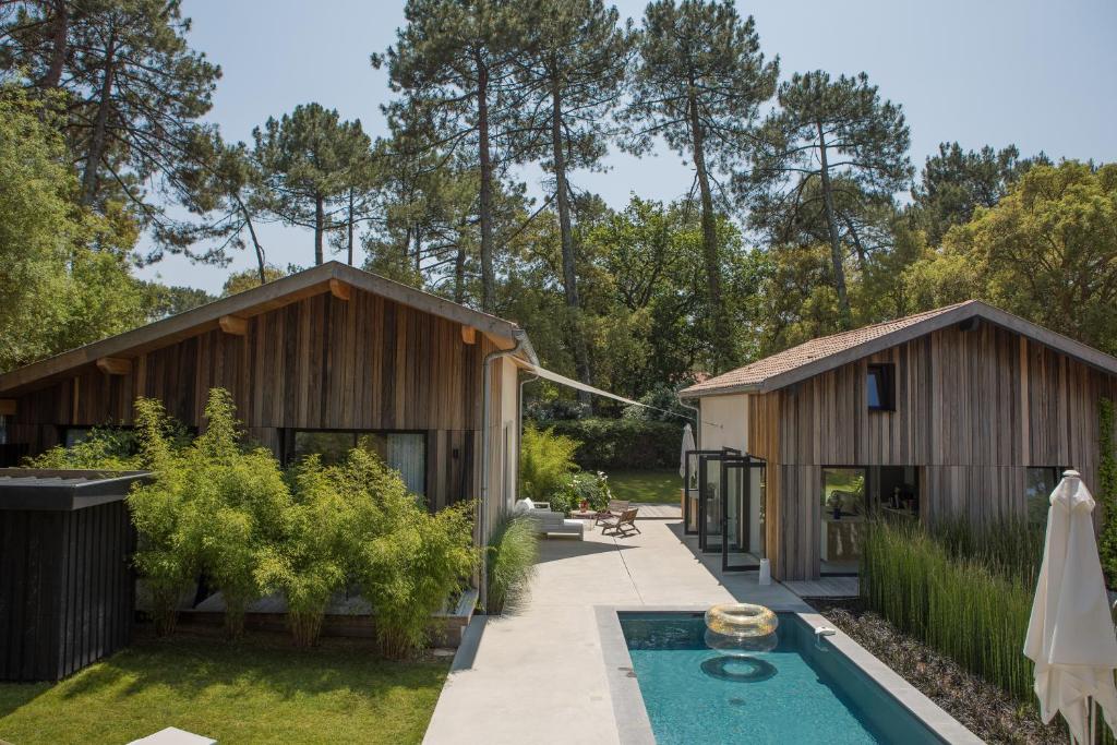 een huis met een zwembad naast twee gebouwen bij Salty Woods Lodge, Chambre d'hôtes in Vieux-Boucau-les-Bains