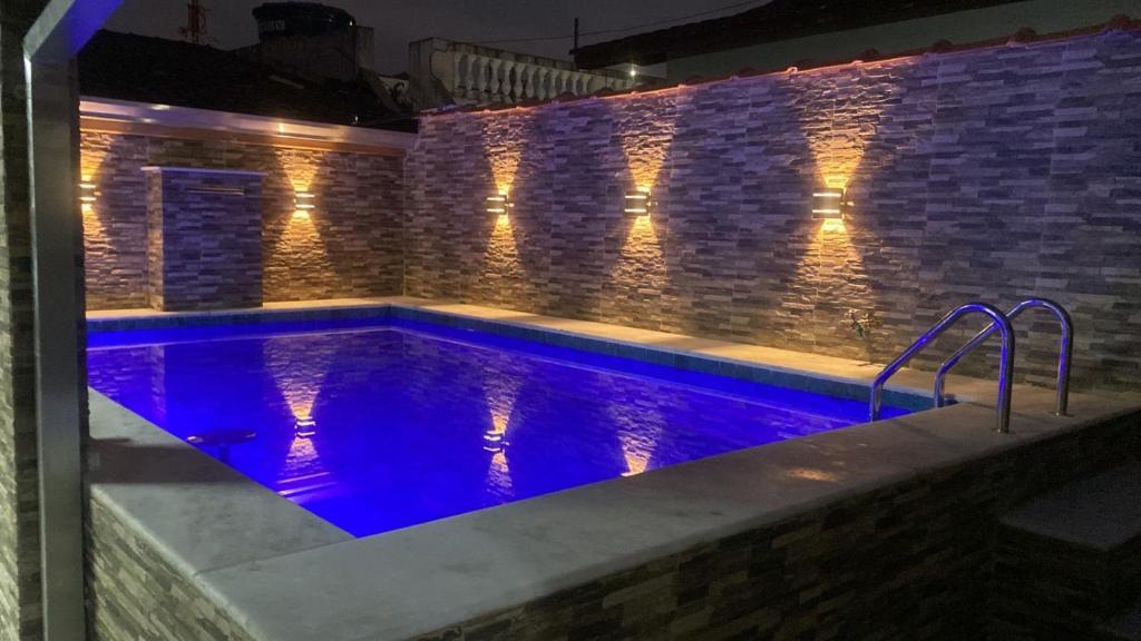 a swimming pool with blue lights on a brick wall at Linda casa de Veraneio in Guarujá