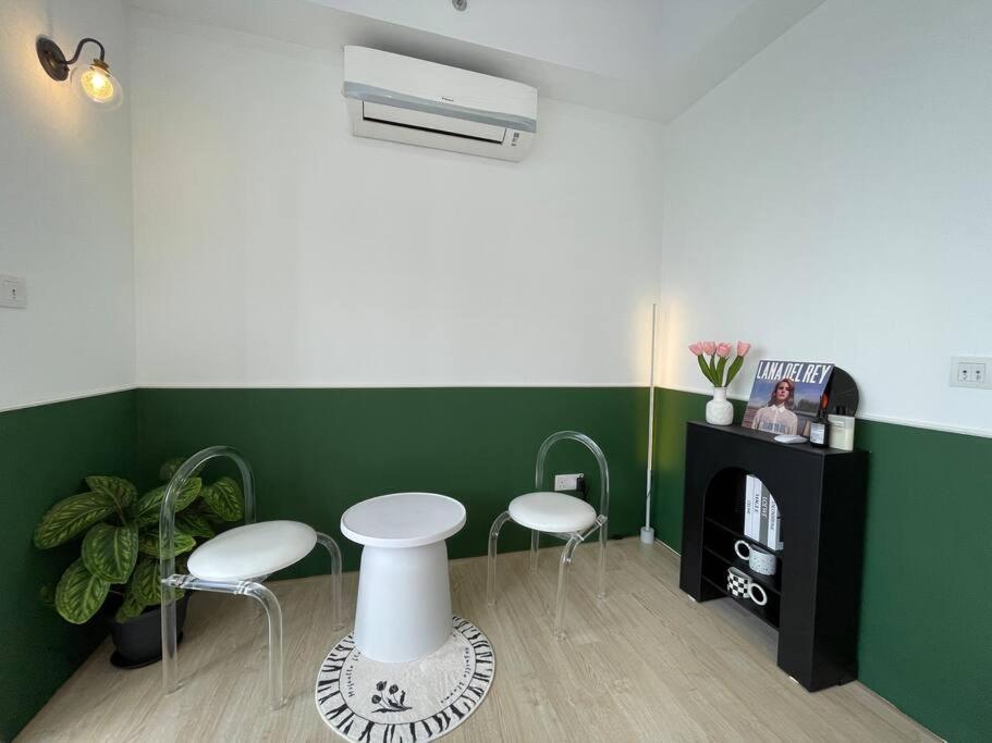 a room with two white stools and a green wall at Pavilion Bukit Jalil Revo@Aurora By D'Summer91 in Kuala Lumpur