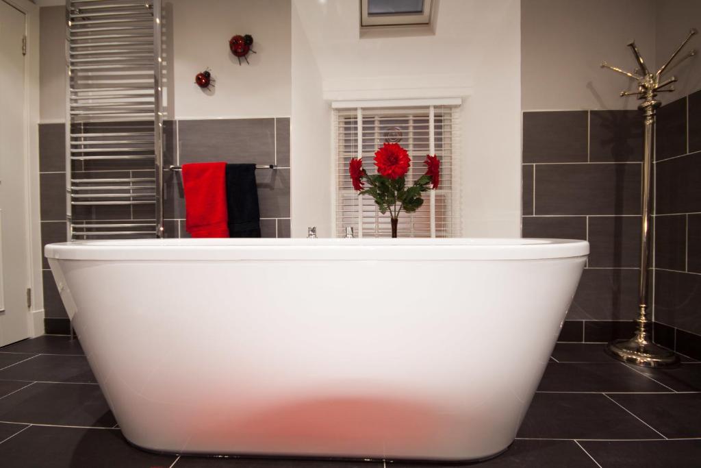 eine weiße Badewanne im Bad mit roten Blumen in der Unterkunft 34 Argyle Guesthouse in St Andrews