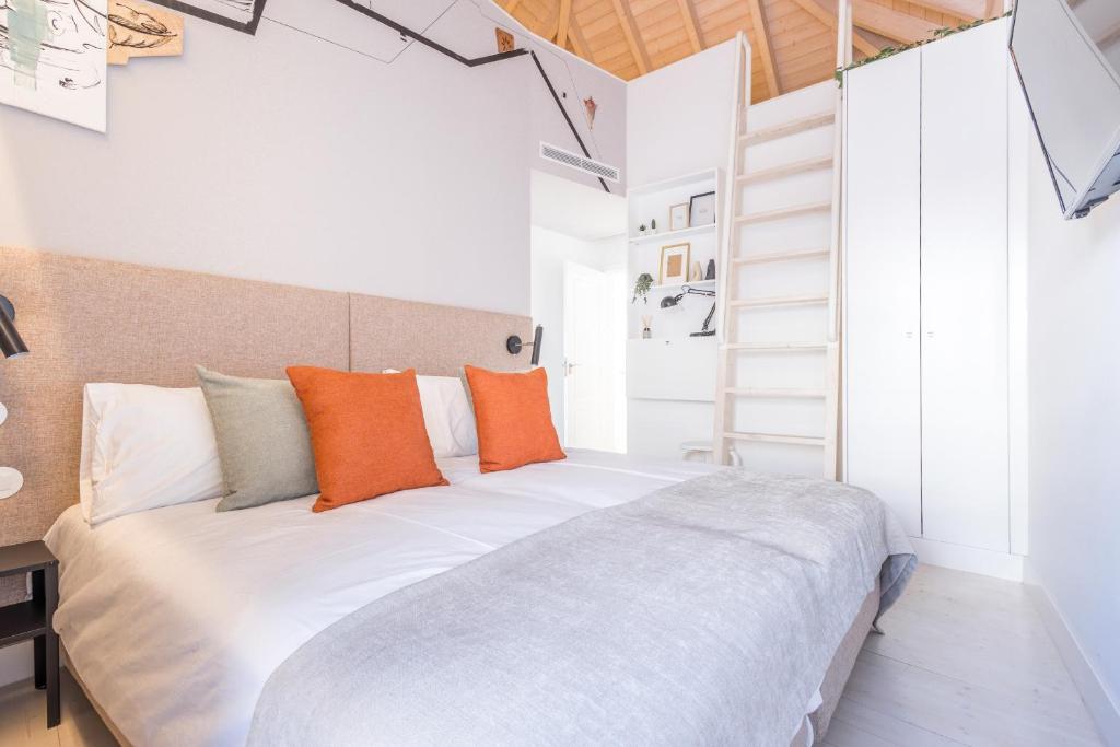 een slaapkamer met een groot wit bed met oranje kussens bij LODO Suits Ala - Studio mezanino by HD in Faro