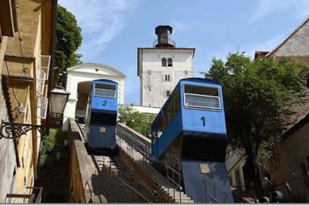 Dos trenes azules están estacionados al lado de un edificio. en Small Peace Oasis en Zagreb