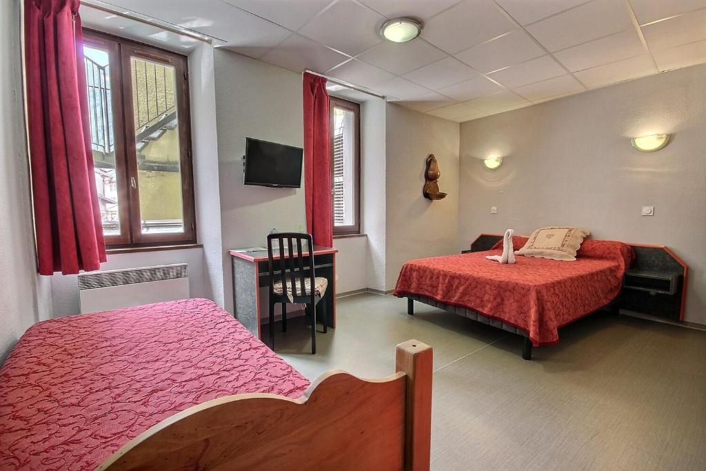 a bedroom with two beds and a table with a desk at Hotel Central in Saint-Pierre-dʼAlbigny