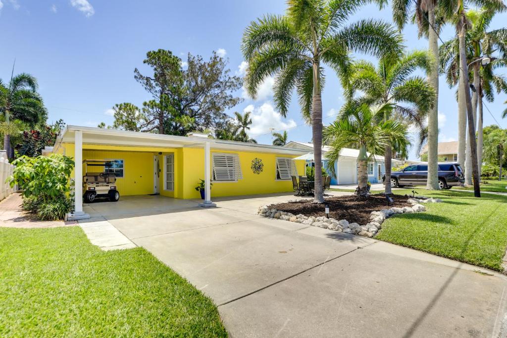 a yellow house with palm trees and a driveway at Bradenton Vacation Rental Gas Grill and Water Views in Bradenton