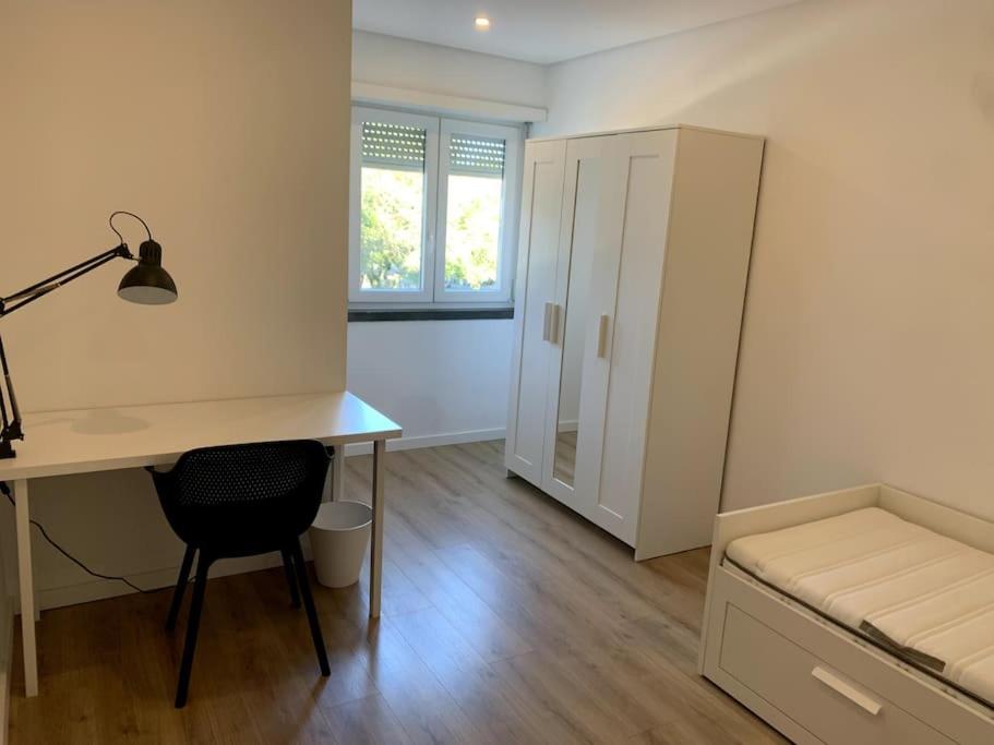 um quarto com uma secretária, uma cama, uma secretária e uma cadeira. em Carcavelos Beach Five Guests apartment em Oeiras