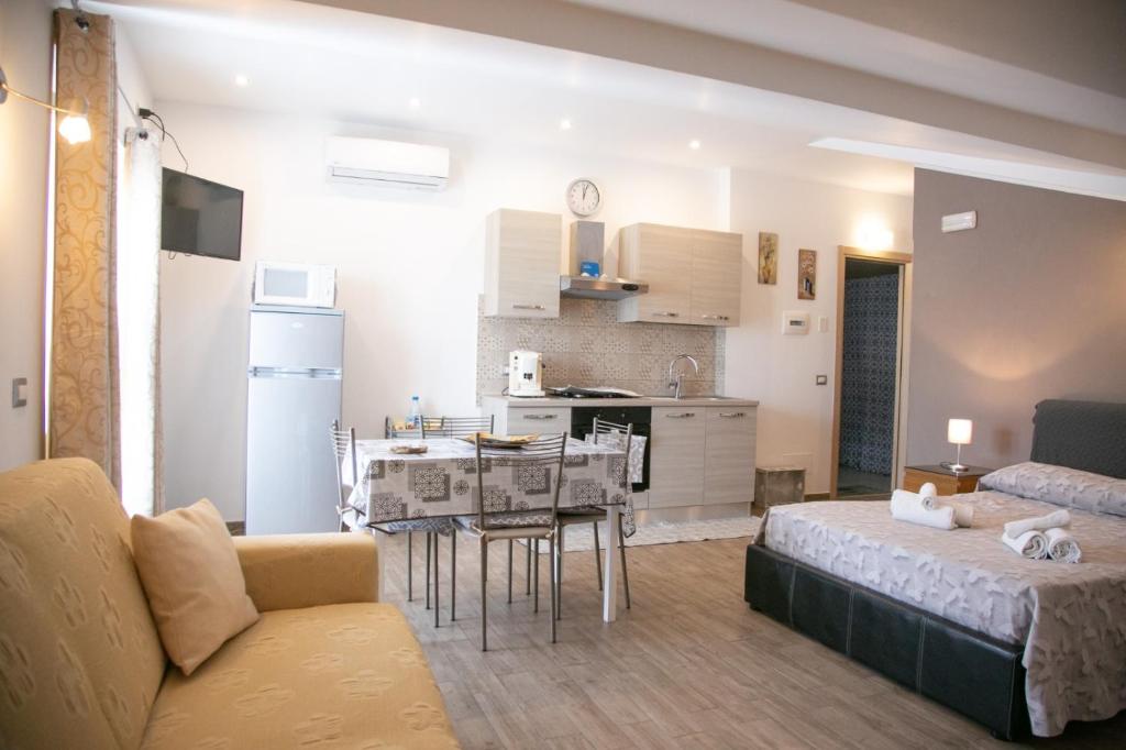 sala de estar y cocina con sofá y mesa en Happy Home en Giardini Naxos
