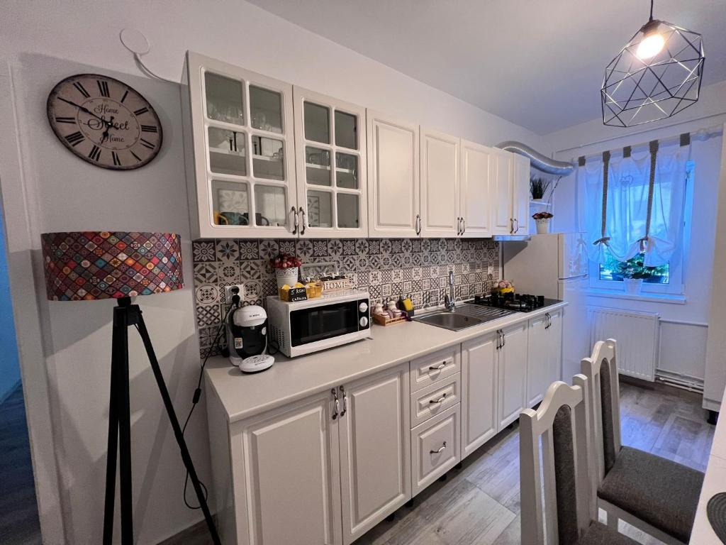 Sweet Home Apartament في بريدال: مطبخ مع دواليب بيضاء وساعة على الحائط