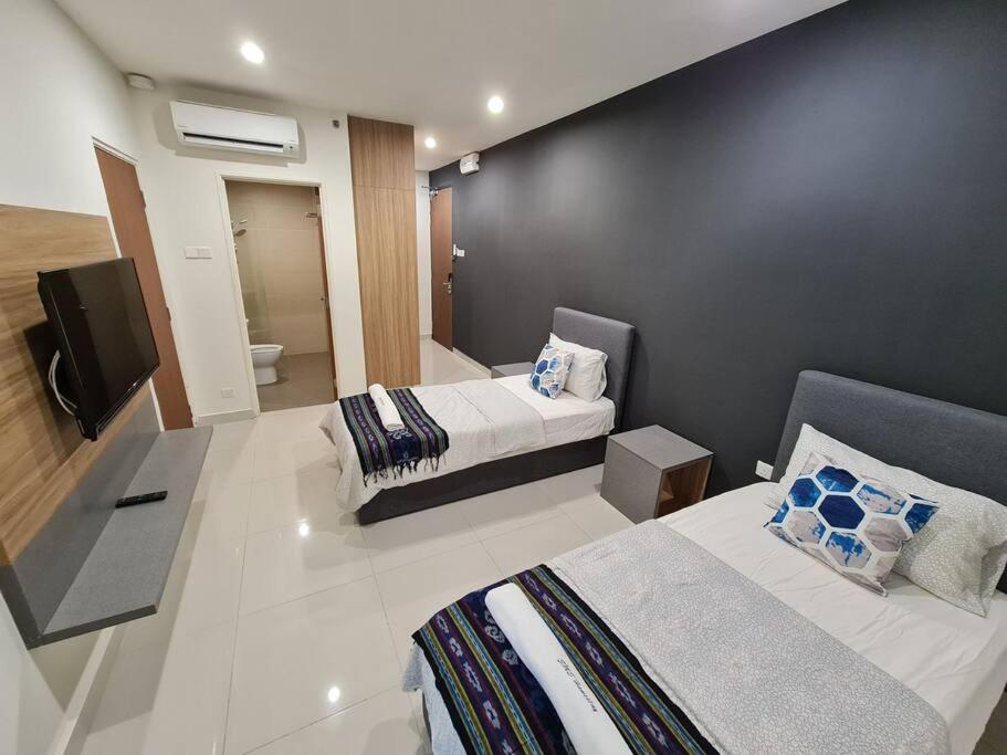 een hotelkamer met 2 bedden en een televisie bij Lovely Kozi Square comfort Studio Home 2A in Kuching