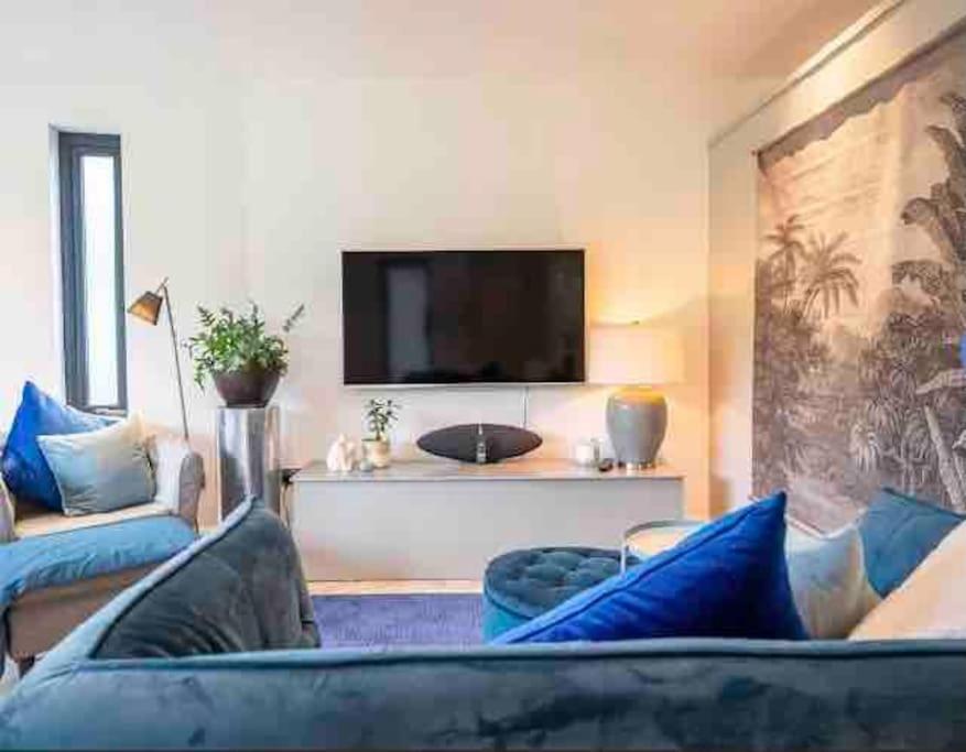 ein Wohnzimmer mit einem blauen Sofa und einem Flachbild-TV in der Unterkunft Beautiful garden apartment with private patio and garden view in Dublin