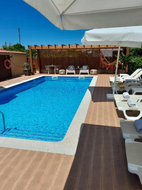 a swimming pool with chairs and an umbrella at Domus Graciosa in Ponte de Lima