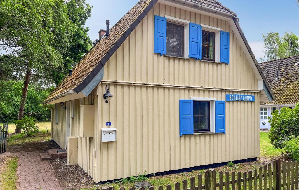 ein Haus mit blauen Fenstern und einem Zaun in der Unterkunft Amazing Home In Prerow With 3 Bedrooms And Wifi in Prerow