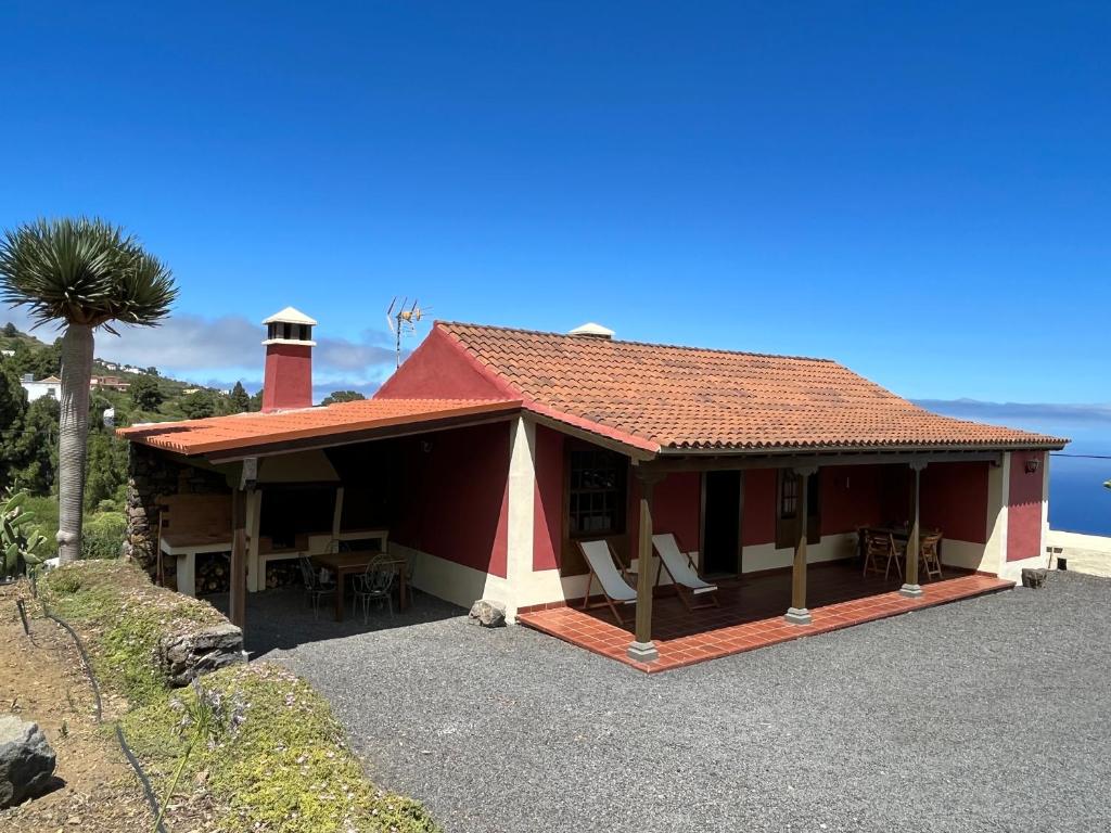 una casa roja y blanca con una palmera en Casa Los Calderos, en Mazo