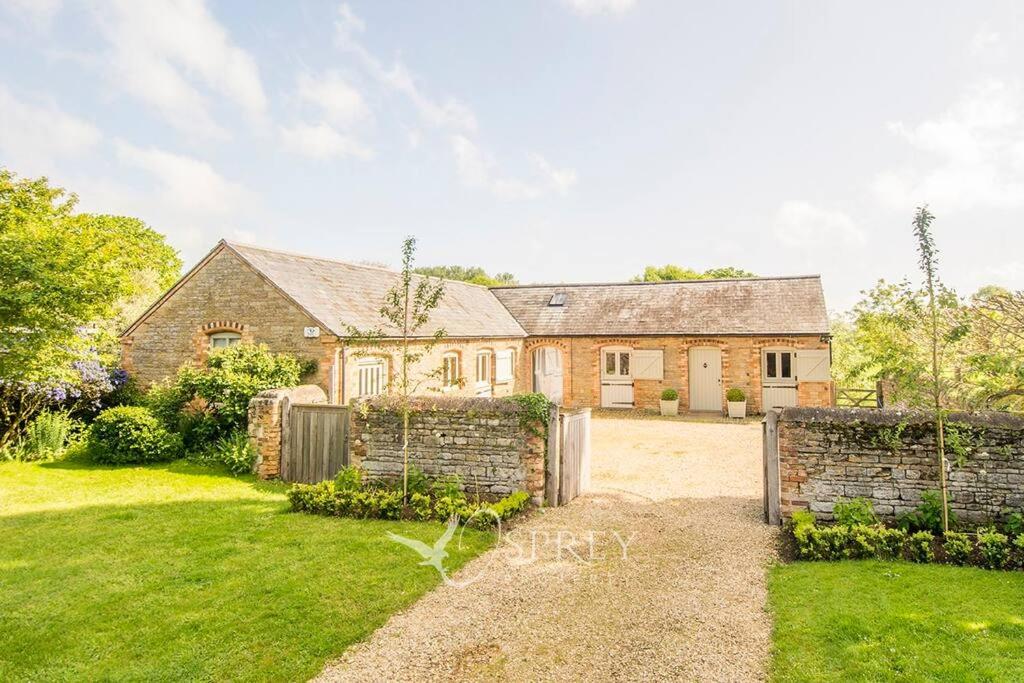 an old brick house with a gate in a yard at Olive in Oundle