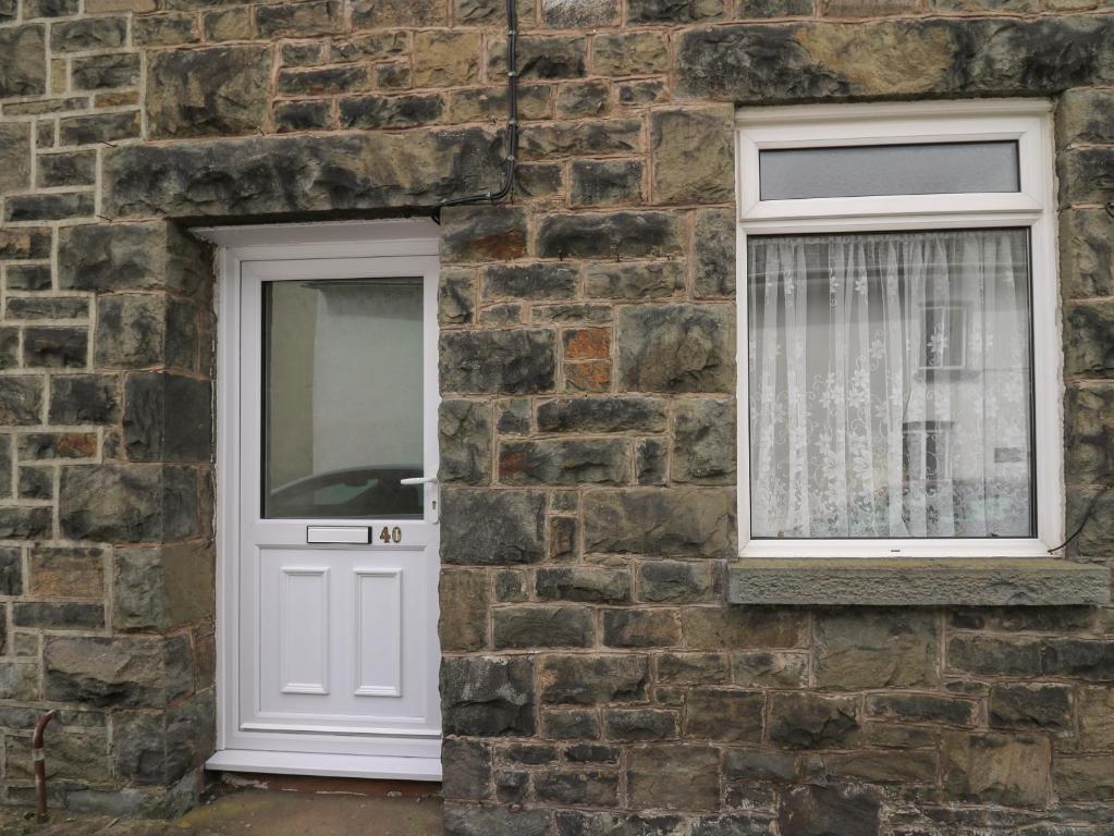 a brick building with a white door and two windows at Rowan Cottage in Builth Wells