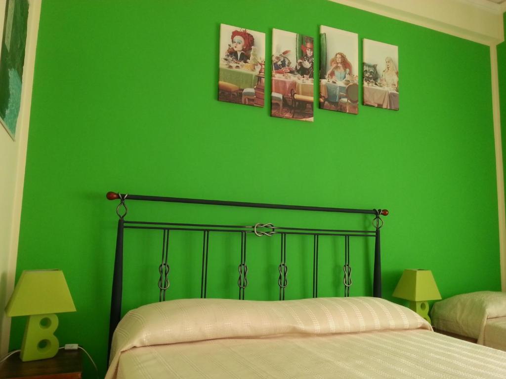 1 dormitorio verde con 1 cama y 4 cuadros en la pared en B&B Intrabartolo, en Trapani