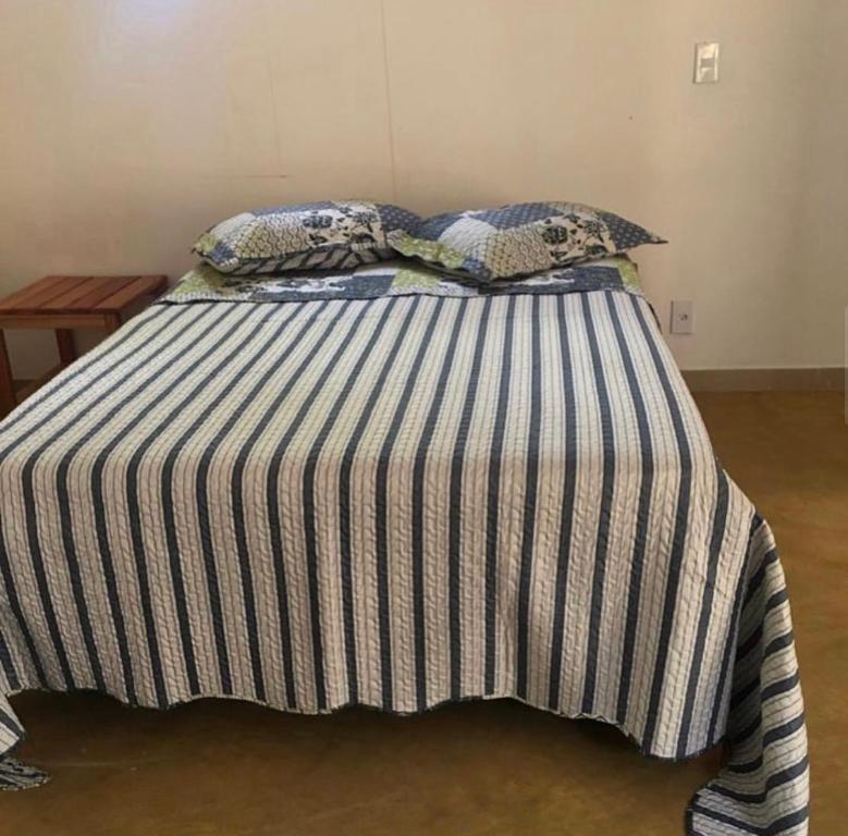 uma cama com um cobertor listrado e almofadas em Pousada Sem Stress Porto Itália em Nova Viçosa