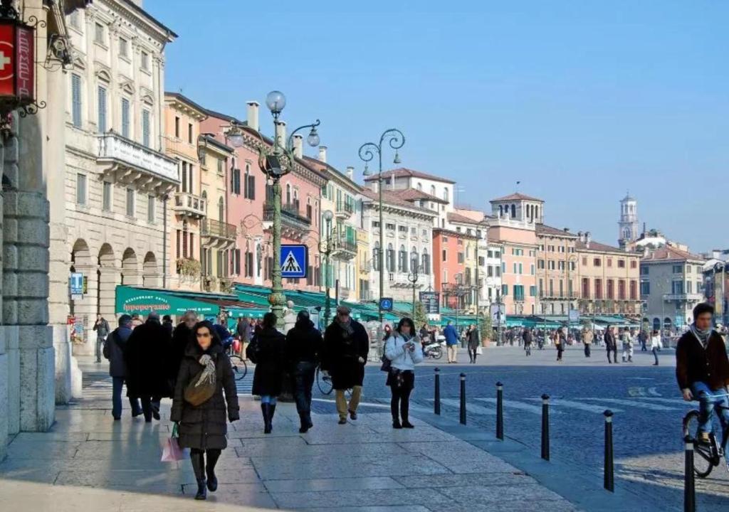 eine Gruppe von Menschen, die eine Stadtstraße entlang laufen in der Unterkunft Arena Maroncelli Rooms in Verona