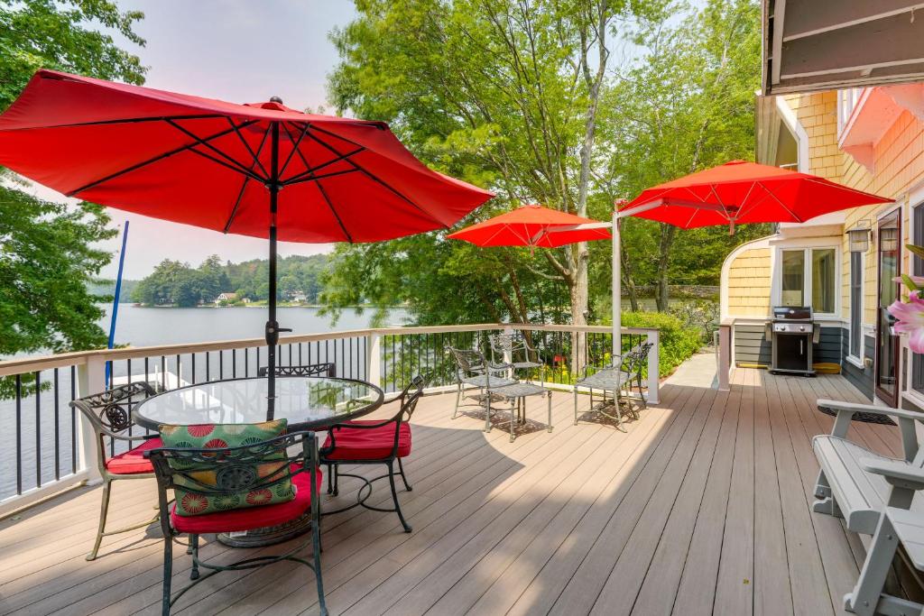 a deck with a table and chairs and umbrellas at Vibrant Sterling Lakefront Lodge with Kayaks in Berlin