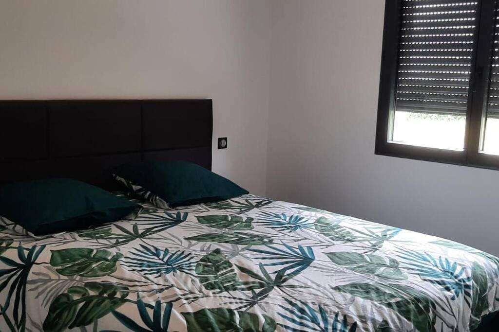 een slaapkamer met een bed met een kleurrijk dekbed en een raam bij Chez Michael in Lunan