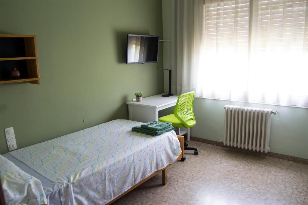 ein Schlafzimmer mit einem Bett, einem Stuhl und einem Schreibtisch in der Unterkunft Habitació V Cal Kim in Martorell