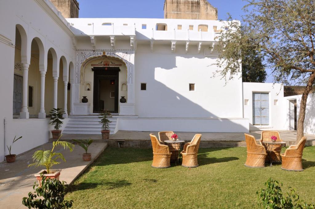 einen Garten mit Stühlen und einem Tisch vor einem Gebäude in der Unterkunft Hotel Chobdar Haveli in Mandāwa