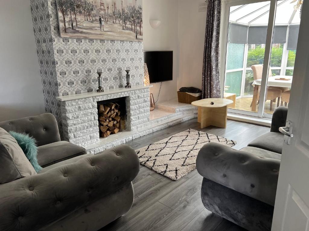 sala de estar con 2 sofás y chimenea en Treetops - Sleeps 8 entire house private parking close to town centre and stadium en Wigan