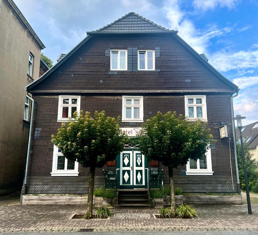 ein Haus mit zwei Bäumen davor in der Unterkunft Hotel Pemü in Arnsberg