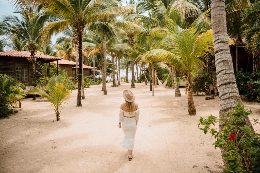 a woman walking down a dirt road with palm trees at Petit Lafitte Beach Front Hotel & Bungalows in Playa del Carmen