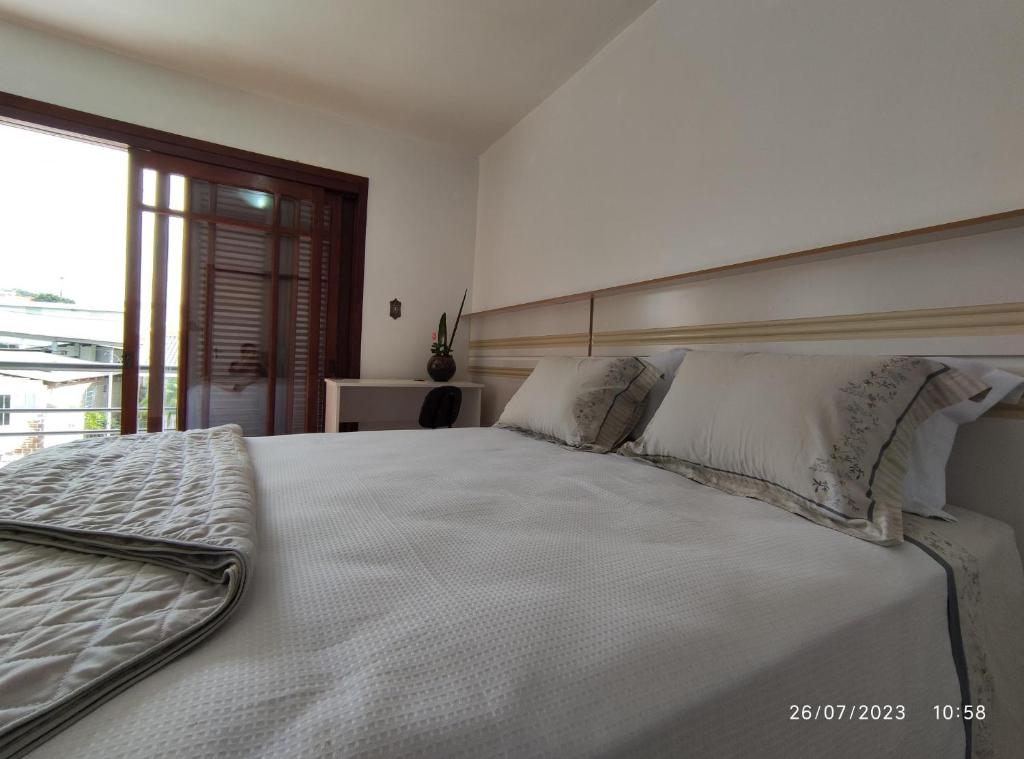 a bedroom with a large white bed with pillows at Pousada com vista para o Cristo 4 in Encantado