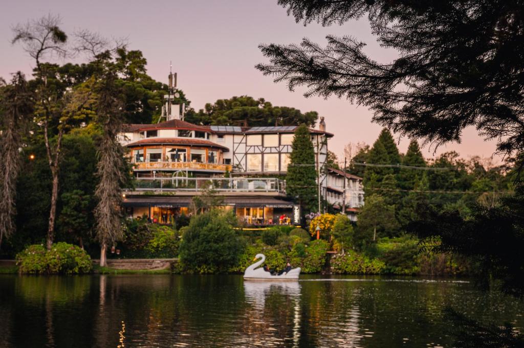 um cisne na água em frente a uma casa grande em Hotel Estalagem St. Hubertus em Gramado