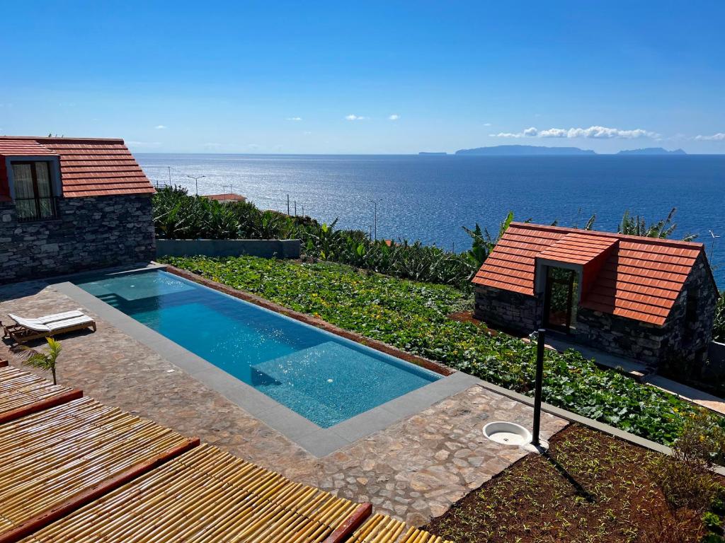 a swimming pool with a view of the ocean at CASAS DO LARANJO- Cottages & Infinity Pool in Gaula