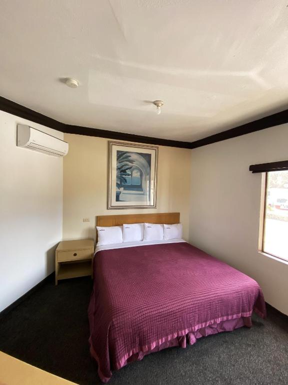 ein Schlafzimmer mit einem großen Bett und einer lila Tagesdecke in der Unterkunft Hotel Coronado in Ensenada