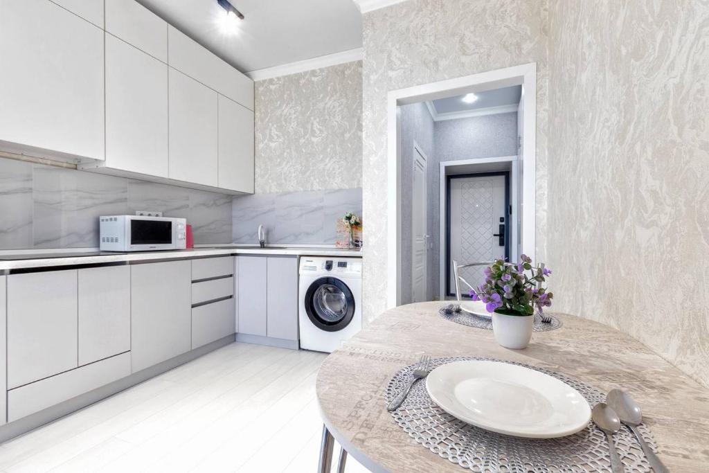 cocina blanca con mesa y lavavajillas en 1 комнатная квартира в ЖК Alma Park, en Taldykolʼ