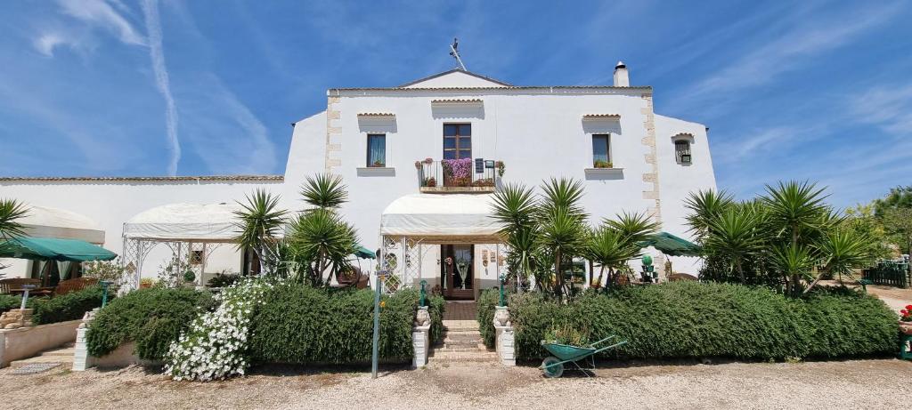 ein weißes Gebäude mit Palmen davor in der Unterkunft Masseria Milu' in Siponto