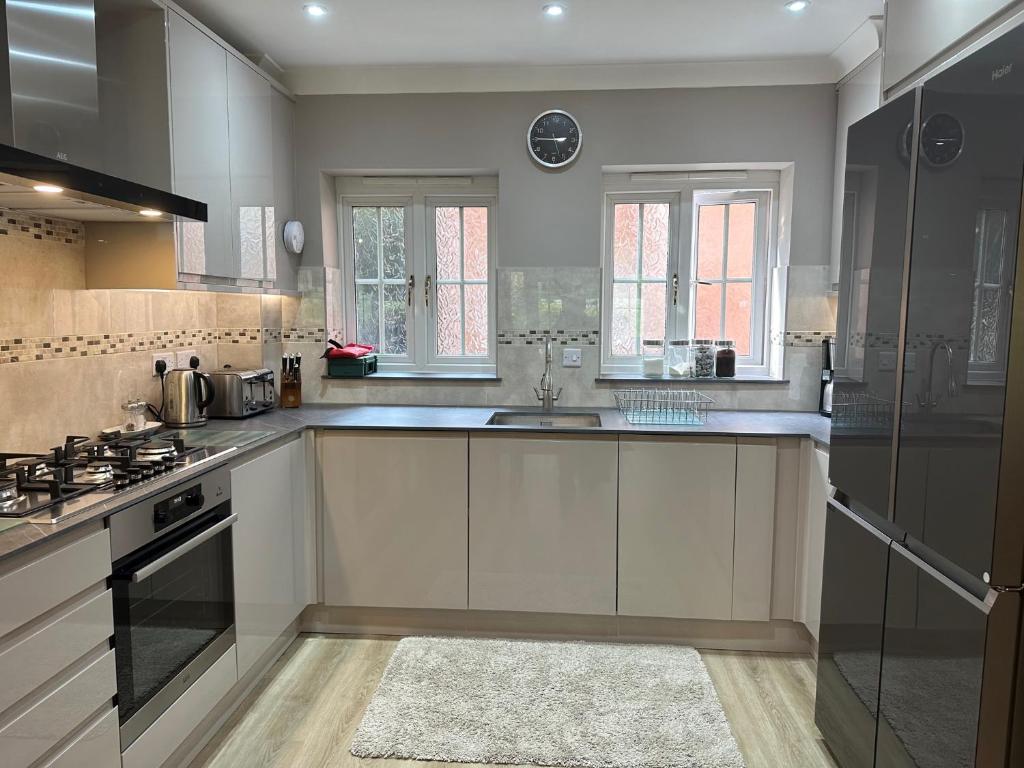 a large kitchen with white cabinets and a sink at The Garden Suite in Basingstoke