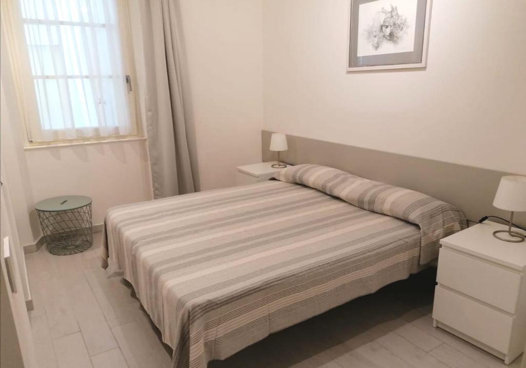 een witte slaapkamer met een bed en een raam bij Appartamento La Corte in Forte dei Marmi