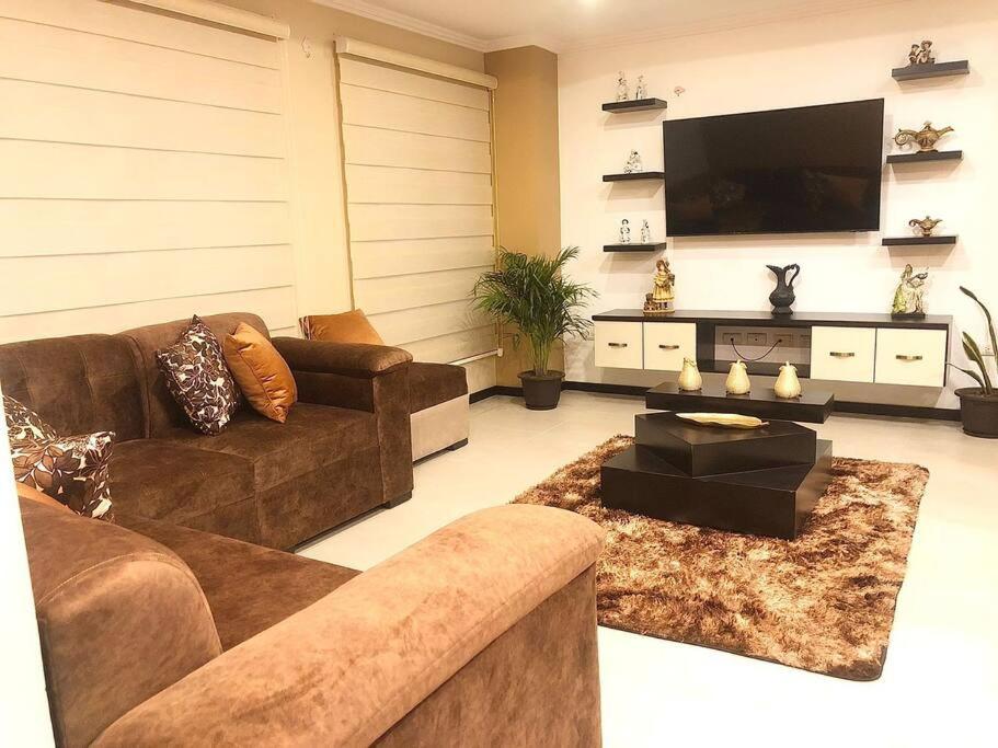 uma sala de estar com sofás e uma televisão de ecrã plano em Condominio La Victoria, departamento em Cuenca