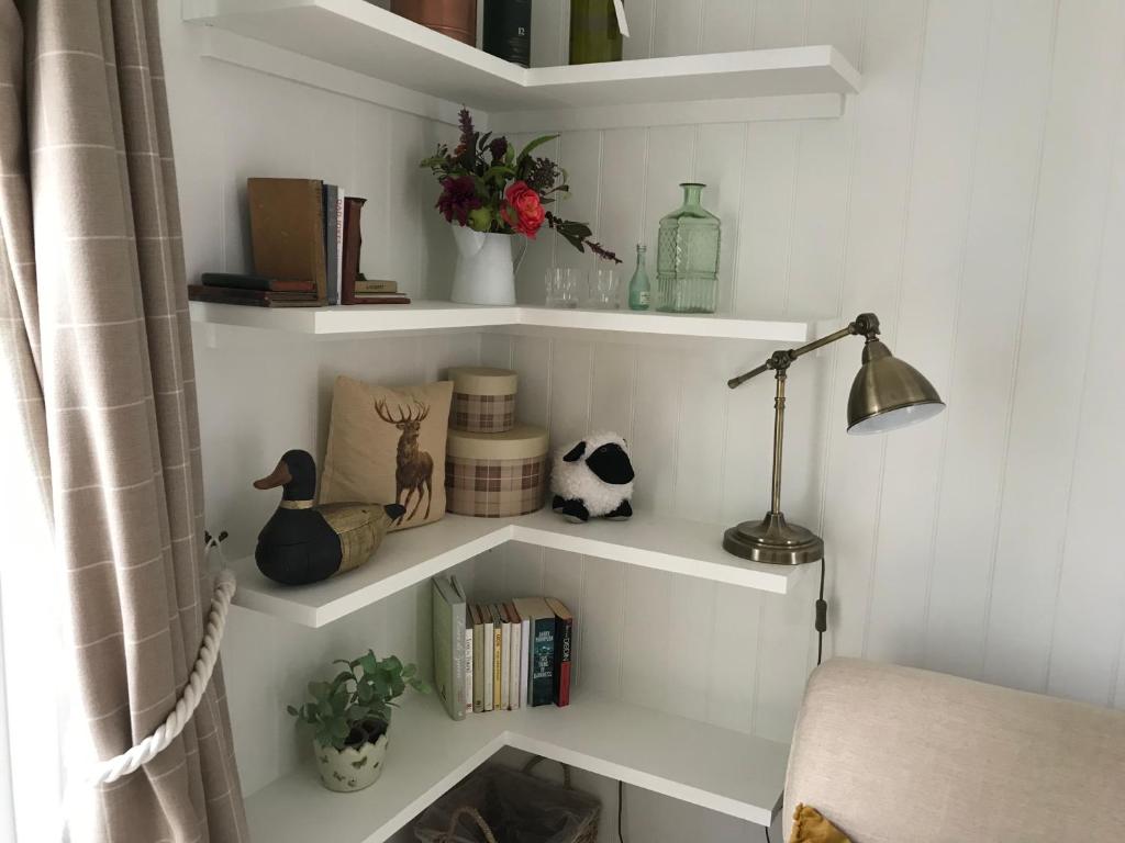 una habitación con estanterías blancas con libros y una lámpara en Wee House in beautiful surroundings Maybole, en Maybole