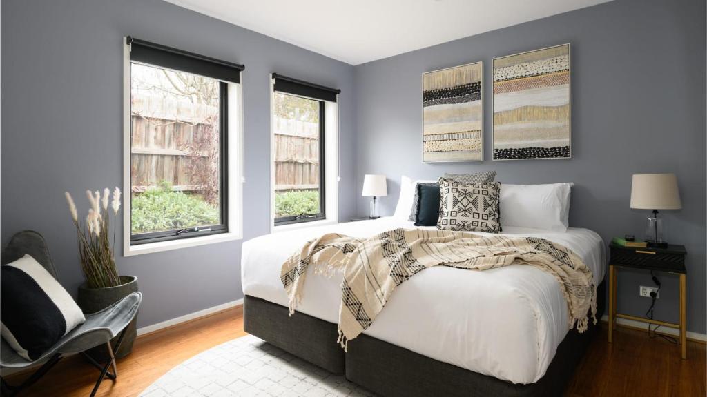 a bedroom with a bed and two windows at Sutton Lodge Daylesford in Daylesford
