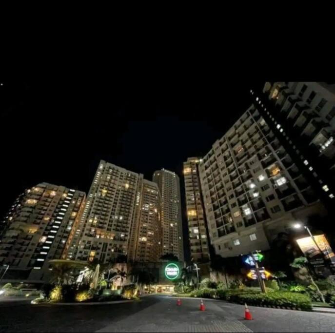 a city at night with tall buildings and a green traffic light at Aussie Shack - 2BR Modern Condo with Skyline View in Manila