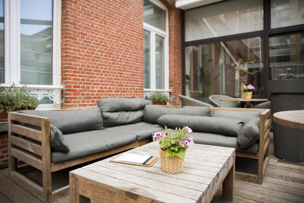 eine Couch auf einer Terrasse mit einem Holztisch in der Unterkunft Alfa Inn in Blankenberge