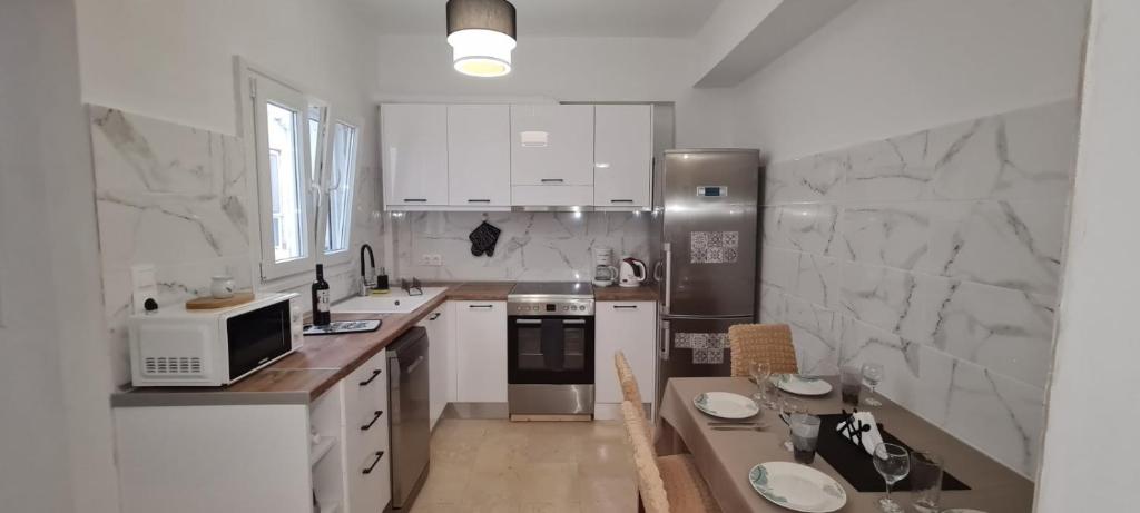 een keuken met witte apparatuur en een tafel. bij Dimitra House Madouki Corfu in Mantoúkion