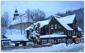 a large wooden building with snow on it at Hotel-Café-Restaurant Parkhaus in Altenau