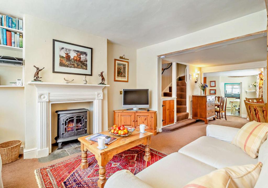 a living room with a couch and a fireplace at Coach House Cottage in Wickham Market