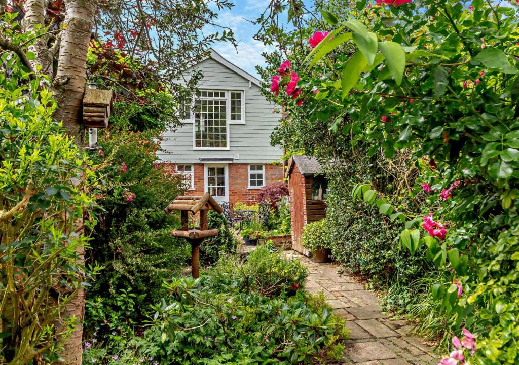 a garden with flowers and a house in the background at Coach House Cottage Annexe in Wickham Market