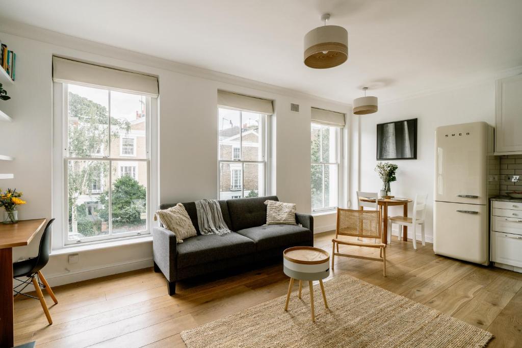 a living room with a couch and a kitchen at Design-led flat in Camden on quiet street in London