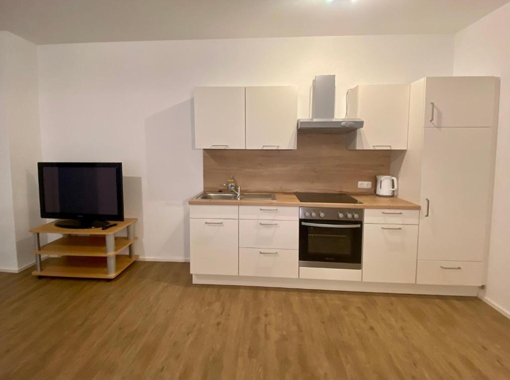a kitchen with white cabinets and a flat screen tv at Ferien-Wohnung für 1-4 Pers in Seenähe in Timelkam