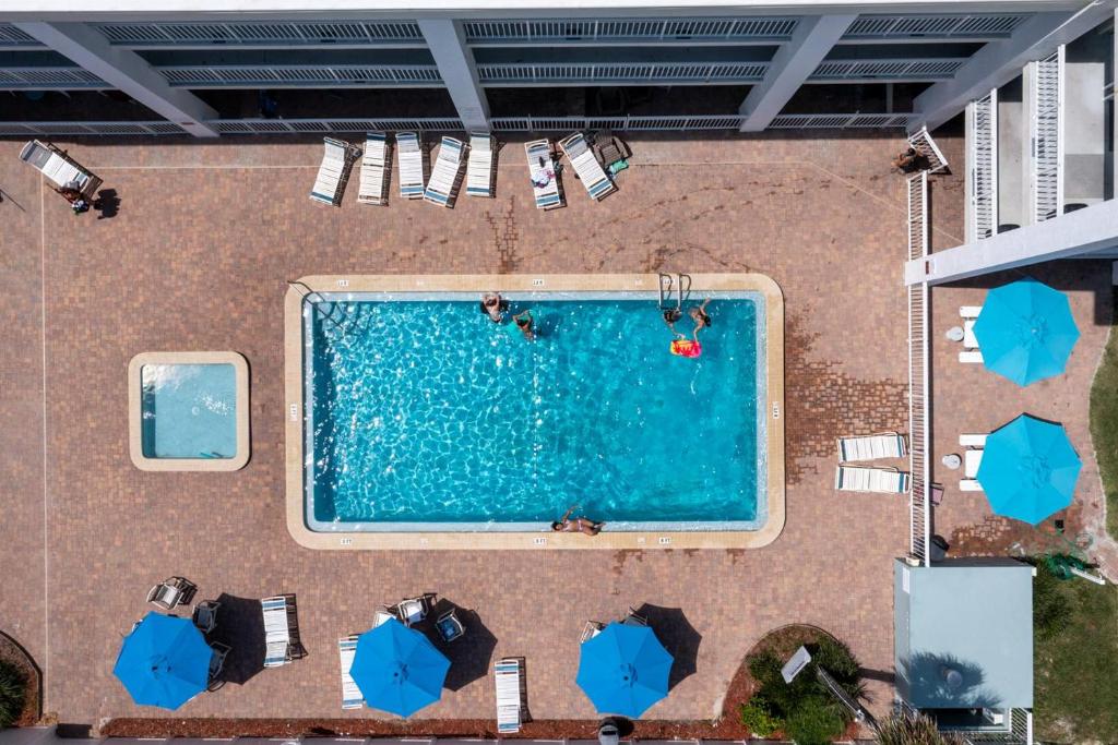 an overhead view of a swimming pool with chairs and umbrellas at Pineapple Pad Studio At Coastal Waters 105 in New Smyrna Beach