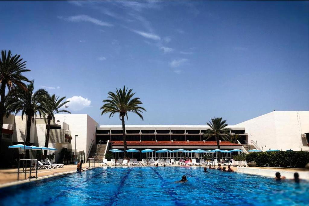 a large swimming pool with palm trees and a building at Vivienda Ida - Costa Del Silencio Tenerife in Costa Del Silencio